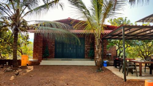 a house with a palm tree in front of it at Saka kadams home stay in Guhagar