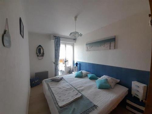 une chambre avec un grand lit avec une tête de lit bleue dans l'établissement Appartement 4 pers, loggia, vue mer, petits chiens admis, ascenseur - FR-1-324A-11, à Saint-Hilaire-de-Riez