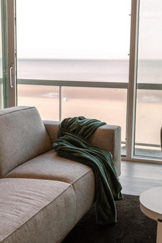 a green blanket sitting on a couch in a living room at Beautiful Luxury Apartment on Amazing location with Sea view - T17 in Ostend