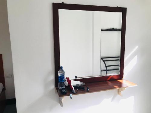 a mirror on a shelf with a bottle of water at Ella Jayamali Holiday Pavilion in Ella