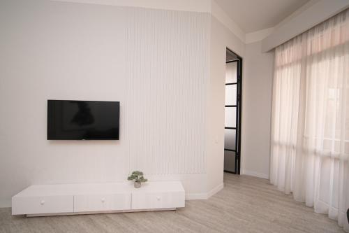 a white living room with a tv on a wall at Sweet Home Apart-Hotel in Yerevan