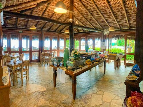una sala da pranzo con tavoli, sedie e finestre di Pousada Vila das Velas a Ilhabela
