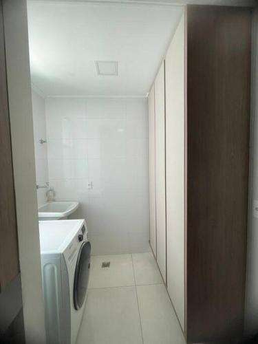 a white bathroom with a washing machine in it at apartamento alto padrão (centro) in Ubá