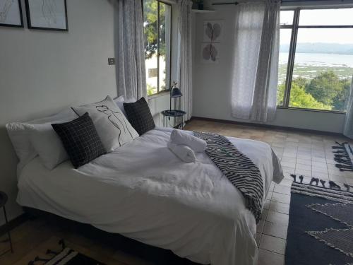 un grand lit dans une chambre avec une grande fenêtre dans l'établissement Dam House Lodge, à Hartbeespoort