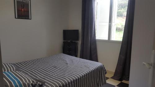 um quarto com uma cama e uma janela com uma televisão em maison T3 500m de la plage em Poggio-Mezzana