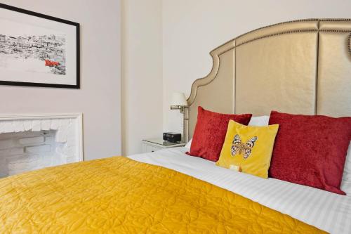 a bedroom with a large bed with red and yellow pillows at Kingston House in Torquay