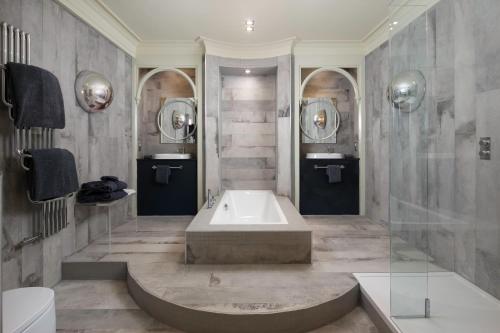 a bathroom with a tub and two mirrors at Talbooth House & Spa in Dedham