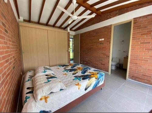 um quarto com uma cama numa parede de tijolos em Casa Campestre Sector Kilometro 41 em Manizales