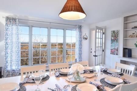 a dining room with a table and chairs and windows at Beautiful Water Views Dogs Welcome in Truro