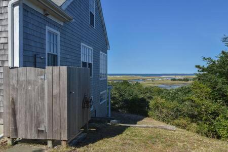 a blue house with a wooden fence in front of it at Beautiful Water Views Dogs Welcome in Truro
