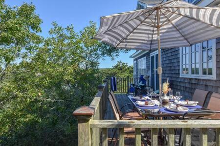 a wooden deck with a table with an umbrella at Beautiful Water Views Dogs Welcome in Truro