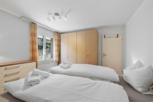 two beds in a bedroom with white walls at Seestrasse 3, Whg 104 in Lenzerheide