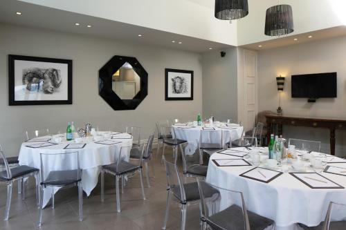 a room with white tables and chairs and a mirror at Talbooth House & Spa in Dedham