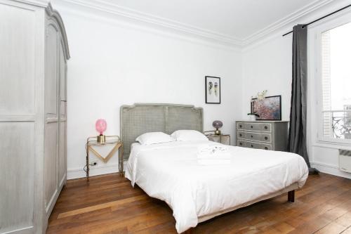 a white bedroom with a large bed and a dresser at Le Bon Marche & St Germain - CityApartmentStay in Paris