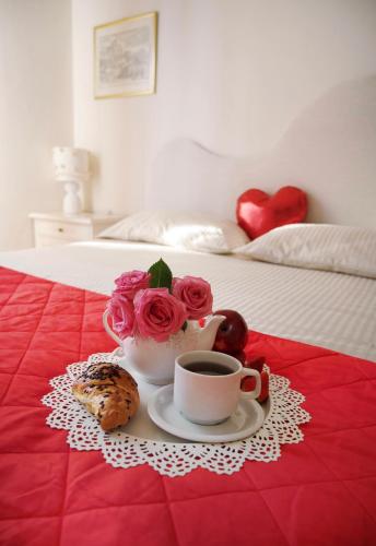 a tray with a cup of coffee and roses on a bed at Il Giardino di Cristina - A literary B&B in Chianti in Vagliagli