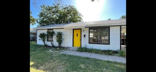 a small white house with a yellow door at Tendayis Paradise - Work Crew Lodging in Abilene