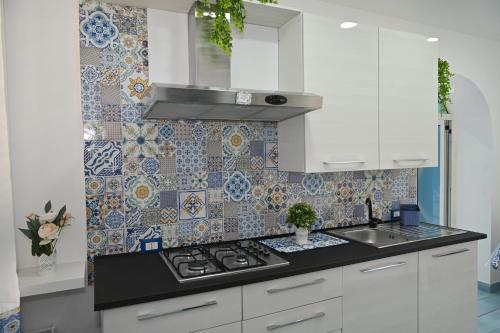 a kitchen with a stove and a tile wall at Vesuvius Dream in Boscotrecase