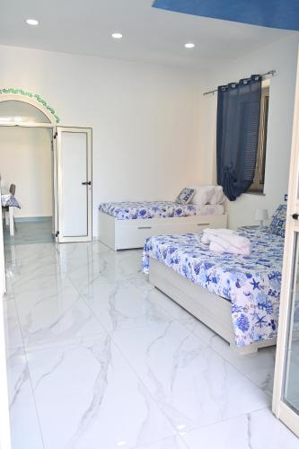 two beds in a white room with marble floors at Vesuvius Dream in Boscotrecase