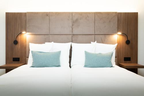 a bedroom with a bed with two blue pillows at Dune Hotel Nieuwpoort in Nieuwpoort