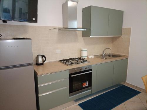 a kitchen with green cabinets and a stove top oven at Da Enza - Appartamento al mare in Grottammare