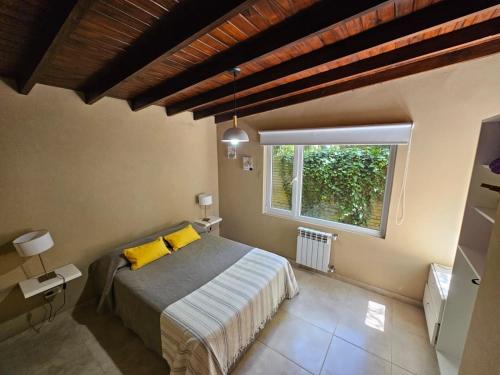 馬德科波的住宿－Cabañas Bosque y Mar，一间卧室配有一张带黄色枕头的床和一扇窗户