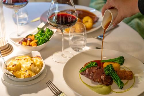 a table with a plate of food and a glass of wine at Talbooth House & Spa in Dedham