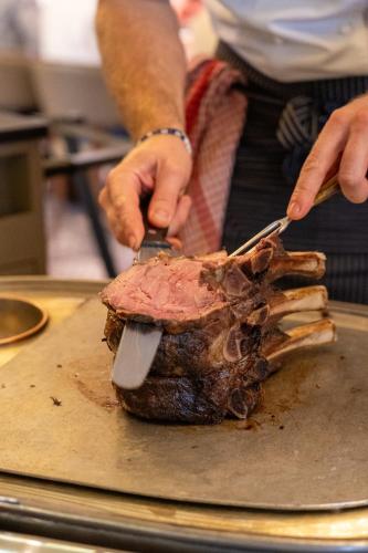 a person cutting a piece of meat with a knife at Talbooth House & Spa in Dedham