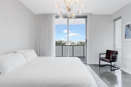 a white bedroom with a bed and a chair at Luxurious Oceanview 1BR Apt with Resort Amenities in Miami Beach