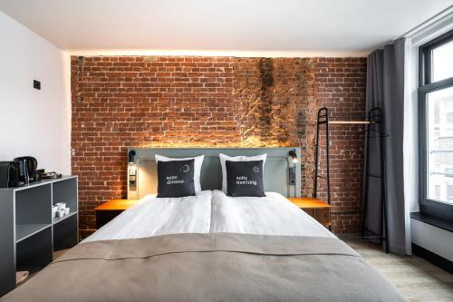 a bedroom with a bed and a brick wall at limehome Amsterdam Leidsekruisstraat in Amsterdam