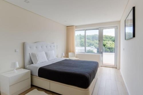 a white bedroom with a large bed and a window at Mifi Beach Luxury Duplex by MP in Vila Nova de Gaia
