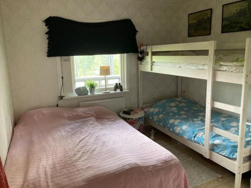 a bedroom with two bunk beds and a window at Stuga i Norra Kvarnviken in Bengtsfors