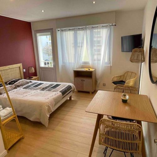 een slaapkamer met een bed en een tafel en stoelen bij Grand studio 1 avec lave-linge in Lorient