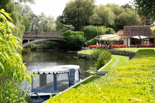 a boat in a river with a bridge in the background at Talbooth House & Spa in Dedham