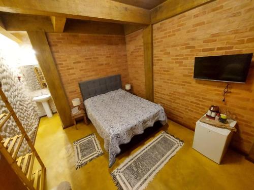 Kleines Zimmer mit einem Bett und einem Flachbild-TV. in der Unterkunft IbitiAnJo - Suítes in Conceição da Ibitipoca