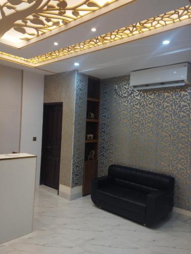 - un canapé noir dans une chambre avec un mur dans l'établissement Hotel White Stone, à Dhaka