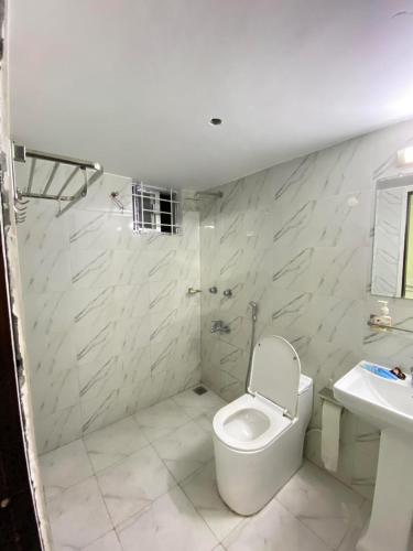 Baño blanco con aseo y lavamanos en Hotel White Stone en Dhaka