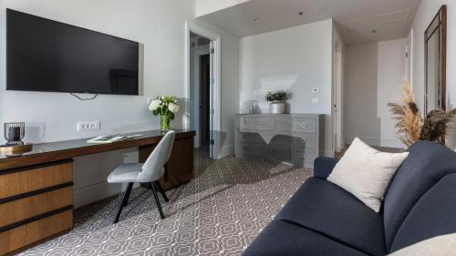 a living room with a blue couch and a desk at Royal Ariston Hotel in Dubrovnik