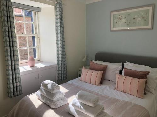 een slaapkamer met handdoeken op een bed met een raam bij Smugglers Neuk - cosy hideaway for 2 in Cellardyke in Cellardyke