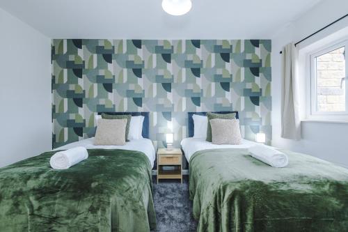 um quarto com 2 camas e lençóis verdes em Charming Home in Mossley with Free Parking and Wi-Fi Sleeps7 em Mossley