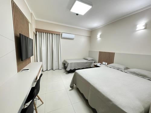 a hotel room with a bed and a desk and a television at Spazzio diRoma - Com acesso ao Acqua park in Caldas Novas