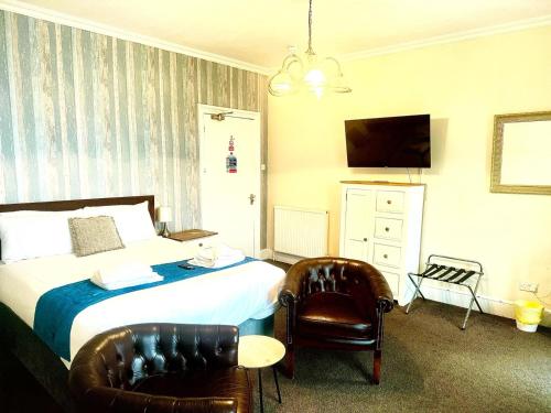 a bedroom with a bed and two leather chairs at The Wash & Tope in Hunstanton