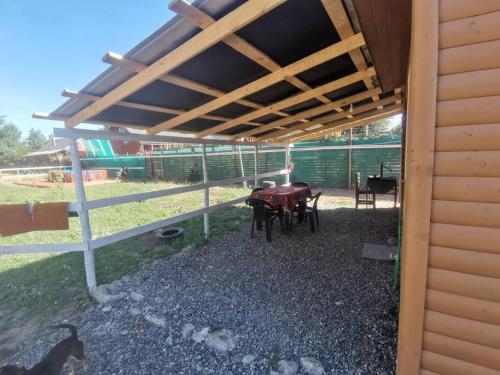 un patio con mesa y sillas bajo toldo en Cabaña El Quillay, en Linares