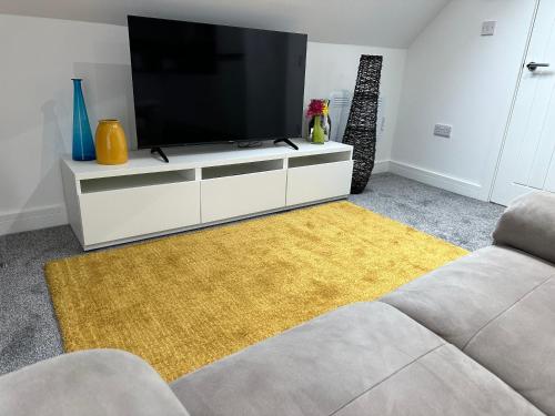 a living room with a flat screen tv on a white cabinet at Vibrant Apartments Close to City Centre in Cardiff