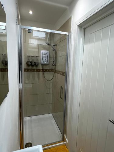 a shower with a glass door in a bathroom at Vibrant Apartments Close to City Centre in Cardiff
