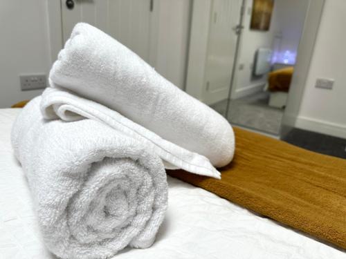 a pile of towels sitting on top of a bed at Vibrant Apartments Close to City Centre in Cardiff