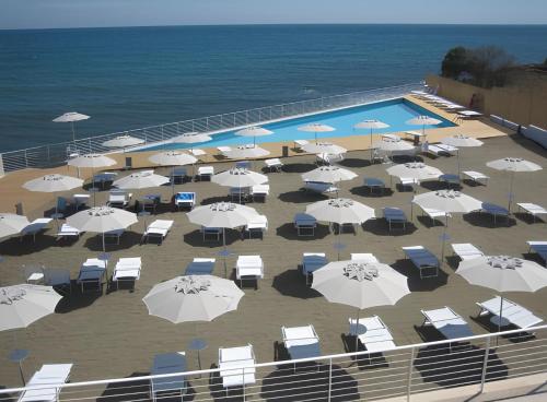 een zwembad met witte parasols en stoelen en de oceaan bij Coastal House - Spiaggia e Piscina a dieci passi in Santa Marinella