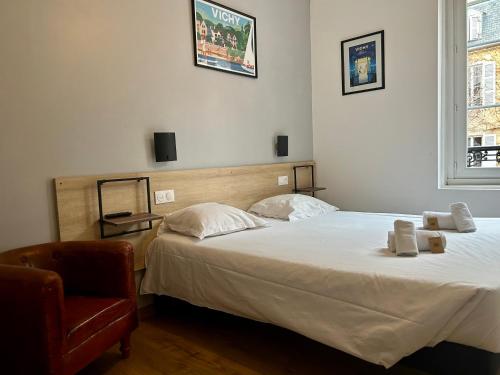 a bedroom with two beds and a chair at Hôtel & Restaurant Le Patio VICHY in Vichy