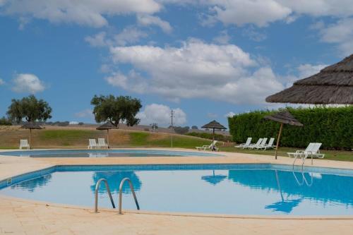 una piscina con sedie e ombrelloni di Em Casa Deles - Herdade do Gizo, Cuba a Beja