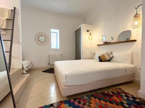 een witte slaapkamer met een bed en een ladder bij Palais Ourikia in Marrakesh