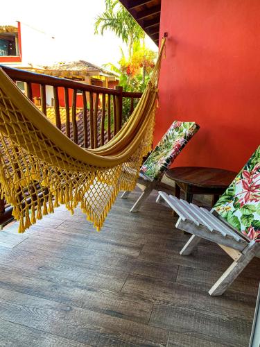 a hammock on a porch with chairs and a table at Pousada Vila das Velas in Ilhabela